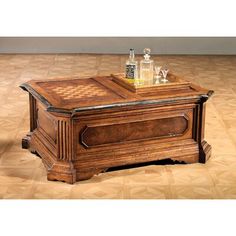 an old wooden box with chess pieces on top and bottles in the middle, sitting on a parquet floor