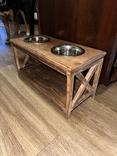 a wooden table with two bowls on it and a dog standing next to the door