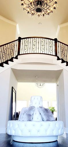 a white couch sitting under a chandelier in a living room next to a stair case