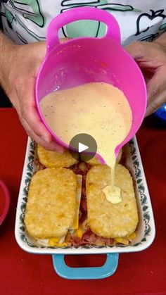 a person pouring sauce on some food in a container