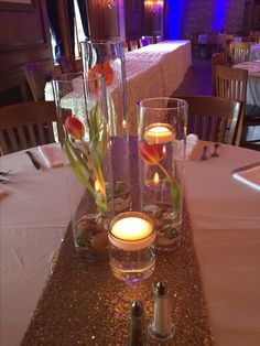 two tall vases with flowers and candles on a table