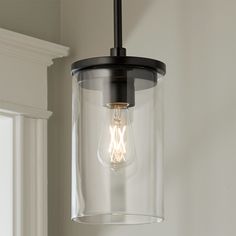 a glass light fixture hanging from the ceiling in a room with white walls and windows