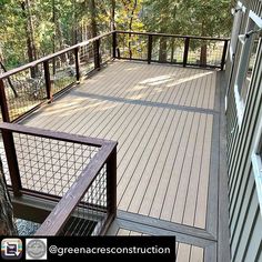 a wooden deck with metal railings next to trees