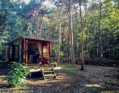 a small cabin in the woods with a picnic table and bench on the ground next to it