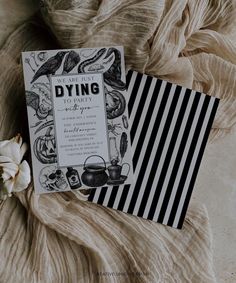 a black and white wedding card on top of a bed next to a small flower