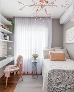 a bedroom with a bed, desk and chair next to a window covered in sheer curtains