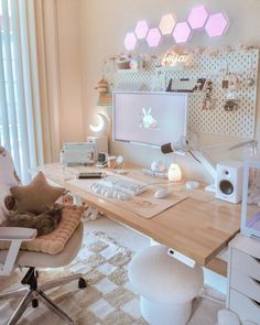 a desk with a computer monitor, keyboard and teddy bear on it in front of a window