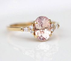 a ring with an oval shaped pink diamond and two smaller round diamonds on each side