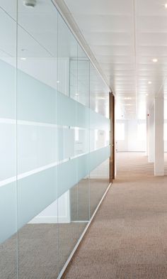 an empty hallway with glass walls and carpet