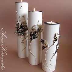 three white vases with flowers on them sitting next to each other in front of a pink background