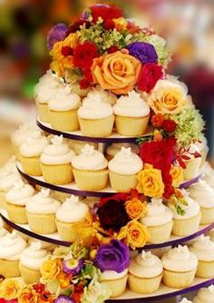 a multi tiered cake with cupcakes and flowers on it