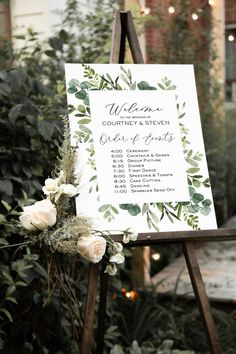 a sign that is on top of a easel with flowers in front of it