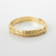 a yellow gold ring with the word mom engraved on it's side and an inscription in