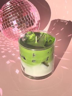 a candle that is inside of a glass with some ice and water in it next to a disco ball