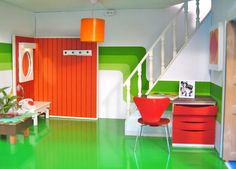 the room is painted bright green and orange with white stairs leading up to an open door