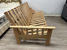 a wooden bed frame sitting on top of a hard wood floor next to a couch