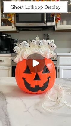 an orange pumpkin sitting on top of a kitchen counter with ghost lollipop display