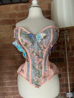 "Stunning one of a kind overbust fairy corset in peach satin, silver iridescent glitter fabric and lace with fairy/butterfly wings attached to the back.   This corset is made with a strength layer of Coutil and is boned with a mixture of flat and spiral steel bones, it is back lacing only with an unboned modesty panel.  The corset measures 25\" at the waist so would probably best suit natural waists in the region of 28-31\"  Fully laced the corset measures   Burt 36\"  Waist 25\"  Upper hip 36\" Fairycore Overbust Corset Dress For Party, Fairycore Overbust Corset, Pink Overbust Corset For Costume, Pink Corset With Corset Back For Costume Party, Fairy Corset, Otherworldly Beauty, Fairy Butterfly, Modesty Panel, Fashion School