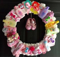 a wreath with baby items hanging from it's side on the front door,