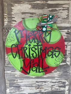 a merry christmas ball door hanger on the side of a wooden door with green and red ornaments