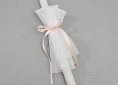 a white candle with a pink ribbon tied around it