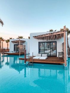 an outdoor swimming pool with chaise lounges and thatched umbrellas next to it