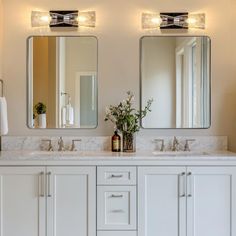 a bathroom with two sinks, mirrors and lights on the wall above them is shown