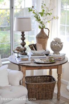 an image of a living room setting with flowers and books on the table, in front of a large window