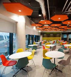 an empty cafeteria with tables and colorful chairs