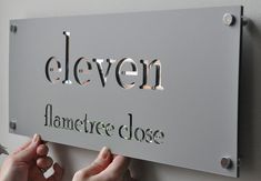 two hands are holding up a sign that says eleven, flamefree close to the wall