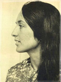 an old black and white photo of a woman with long hair wearing a floral shirt