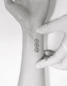 a woman's wrist tattoo with three circles on the left side of her arm