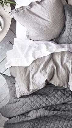 an unmade bed with pillows and blankets on top of it, next to a plant