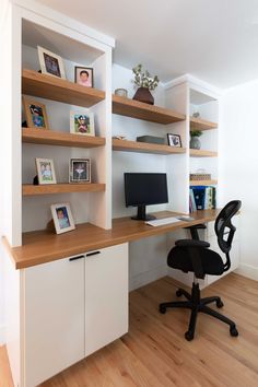 a home office with white shelving and wooden flooring, along with a black chair