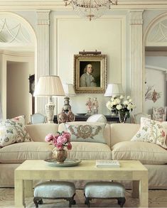 a living room filled with furniture and a chandelier above a coffee table in front of a painting