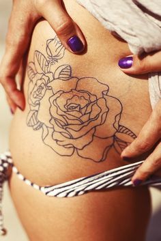 a close up of a person's stomach with tattoos on her belly and flowers