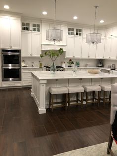 a large kitchen with white cabinets and wooden floors