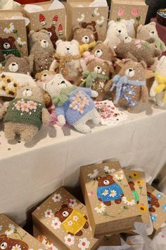 there are many small teddy bears on display at the table with little boxes in front of them