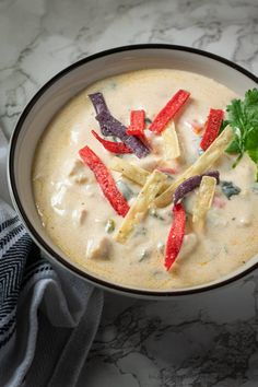 a bowl filled with soup and garnished with cilantro, red peppers and parsley