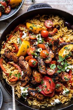 a skillet filled with chicken, tomatoes and pasta