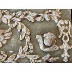 an intricately carved piece of stone with leaves and flowers on the sides, is shown