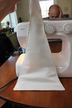 a man is working on a sewing machine with white cloth over the front of it