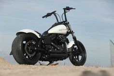 a white and black motorcycle parked on top of a sandy beach next to the ocean