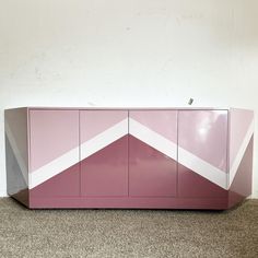 a pink and white cabinet sitting on top of a carpeted floor next to a wall