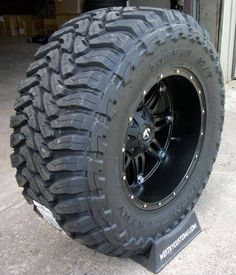 a large truck tire sitting on top of a metal stand in front of a garage