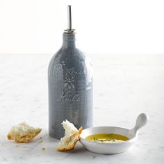 a bottle with some bread in it next to a bowl and spoon on a table