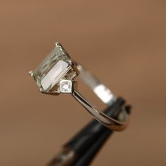 It is a natural green amethyst. The main stone is 6mm*8mm emerald cut, weight about 1.54 carats. The basic metal is sterling silver and plated with rhodium. To change the metal to a solid gold (white/rose) or platinum is also available, please ask for a quotation if you want. You can also go to my shop Home for more elegant rings: https://www.etsy.com/shop/godjewelry?ref=hdr_shop_menu Customization is always welcome and please feel free to contact with me if you have any design ideas! Emerald Cut Amethyst Ring For Formal Occasions, Green Emerald-cut Amethyst Ring For Wedding, Emerald Cut Amethyst Ring In White Gold, Wedding Emerald Cut Green Amethyst Ring, Wedding Green Emerald-cut Amethyst Ring, Wedding Green Emerald Cut Amethyst Ring, Elegant Solitaire Amethyst Ring With Emerald Cut, Green Emerald-cut Amethyst Ring For Anniversary, Green Emerald Cut Amethyst Ring For Anniversary