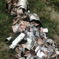 a pile of wood sitting on top of a grass covered field next to a fire hydrant