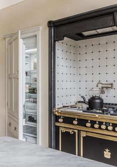 an old fashioned stove in the middle of a kitchen with black and white tiles on the wall