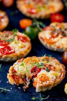 several mini pizzas with different toppings on a blue tablecloth next to tomatoes and lemons